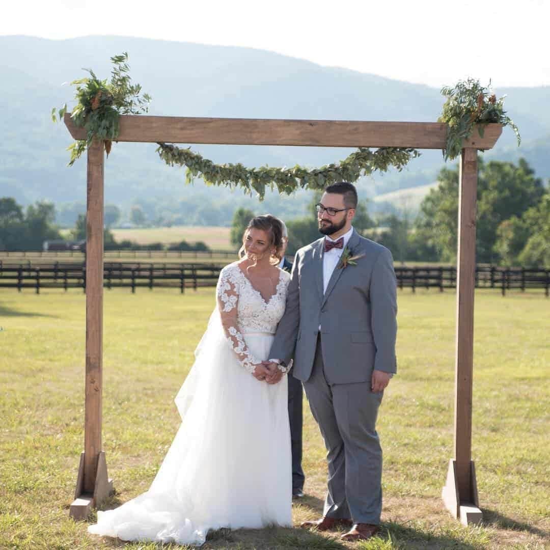 Couple holds hands as they exchange vows outside at King Family Vineyards with the horses and Virginia Mountain views in the background. 