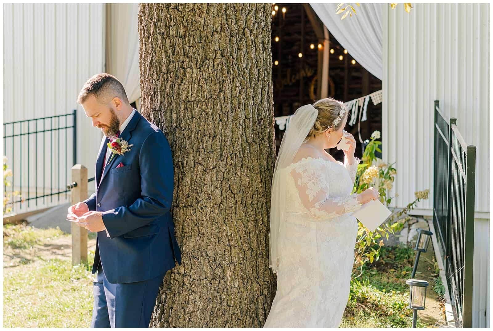 Bride and groom wipe tears away during first touch -- an alternative to a first look -- from around a tree at mount solon's mountain view farm