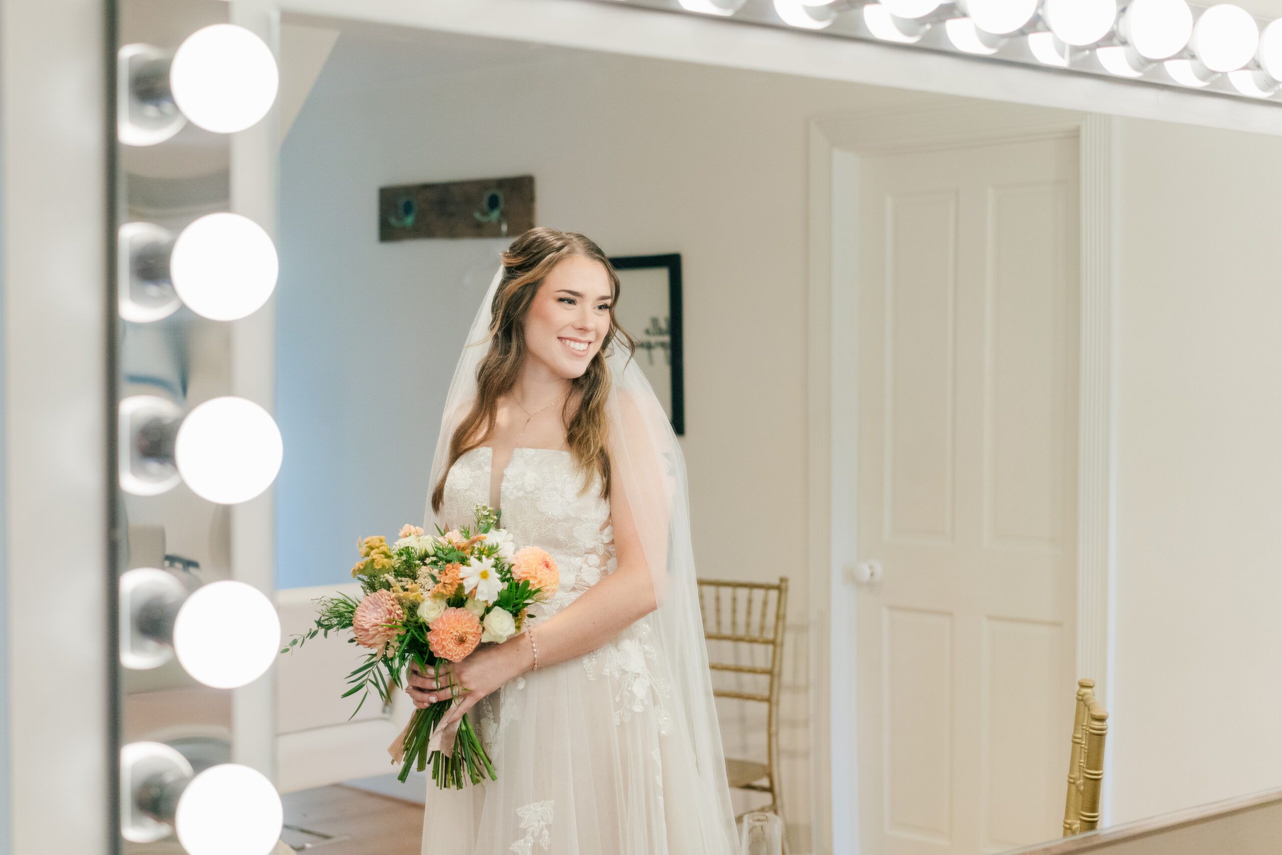 Woman in wedding gown looks in the vanity mirror at Red August Farm, a Waynesboro, Virginia wedding venue.