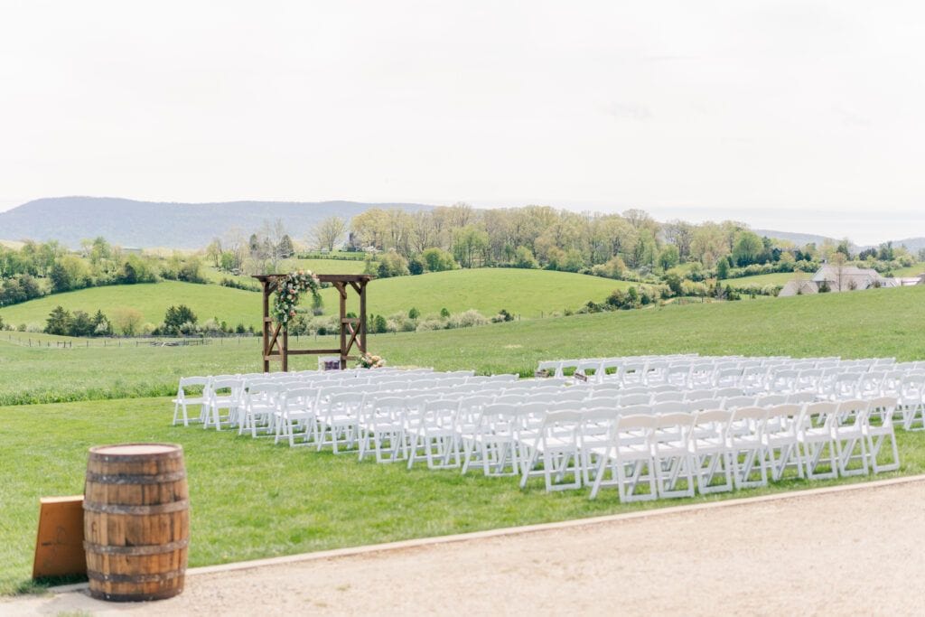 Outdoor wedding ceremony location with mountain views at Sky Ridge Farm in Waynesboro, VA, decorated with wooden barrels and ceremony aisle florals. Photo by Wedding Phootography by Jo Mahaney, a Virginia wedding photographer.