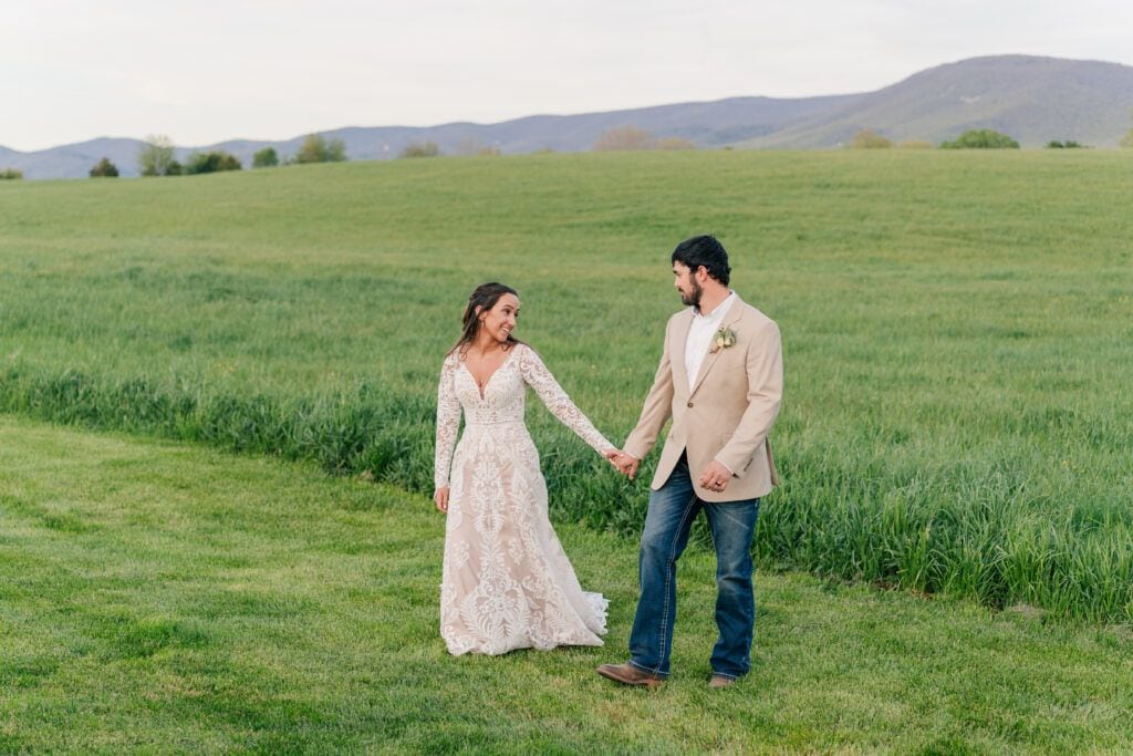 Walking hand in hand at sunset at Sky Ridge Farm, a barn wedding venue in Waynesboro, VA, near the Blue Ridge Mountains. Photo by Wedding Phootography by Jo Mahaney, a Virginia wedding photographer.