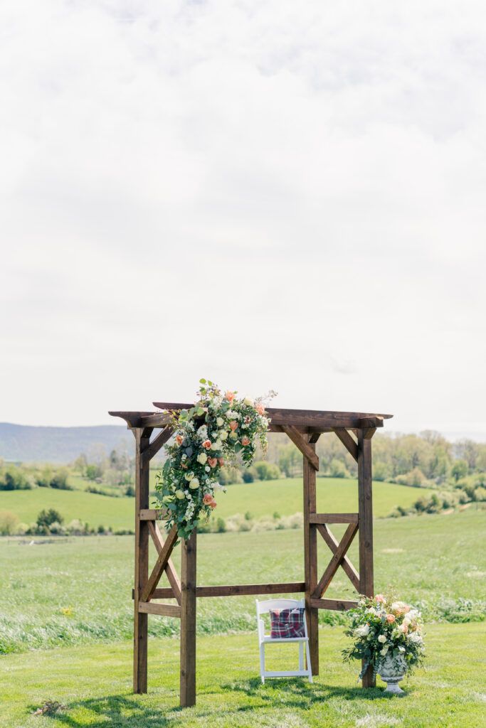 Wedding ceremony florals on dark wooden arch structure at Sky Ridge Farm, a barn wedding venue in Waynesboro, VA, near the Blue Ridge Mountains. Photo by Wedding Phootography by Jo Mahaney, a Virginia wedding photographer.