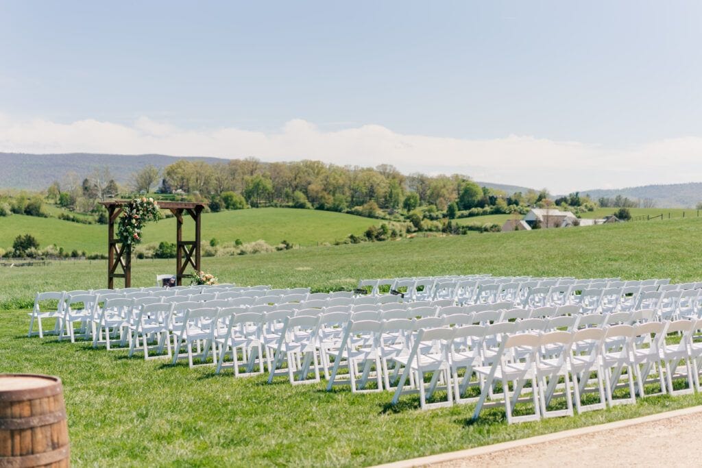Outdoor wedding ceremony location with mountain views at Sky Ridge Farm in Waynesboro, VA, decorated with wooden barrels and ceremony aisle florals. Photo by Wedding Phootography by Jo Mahaney, a Virginia wedding photographer.