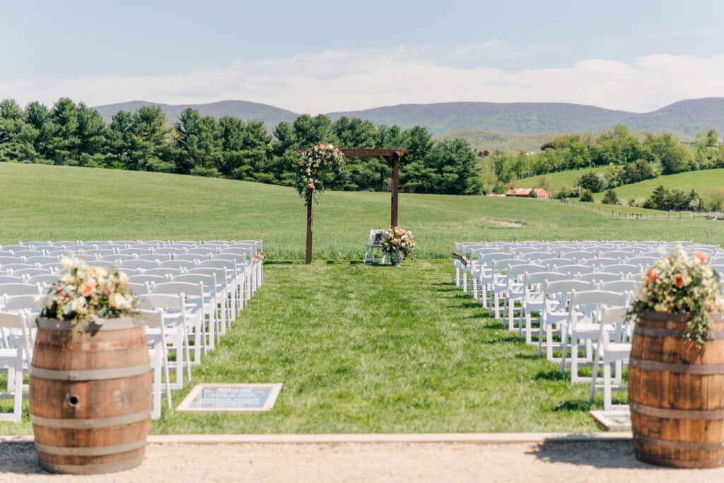 Outdoor wedding ceremony location with mountain views at Sky Ridge Farm in Waynesboro, VA, decorated with wooden barrels and ceremony aisle florals. Photo by Wedding Phootography by Jo Mahaney, a Virginia wedding photographer.