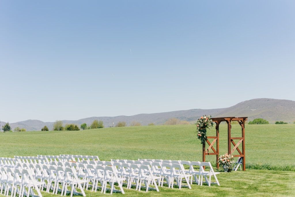 Wedding ceremony setting with white chairs and minimal florals at Sky Ridge Farm, a barn wedding venue in Waynesboro, VA, near the Blue Ridge Mountains. Photo by Wedding Phootography by Jo Mahaney, a Virginia wedding photographer.