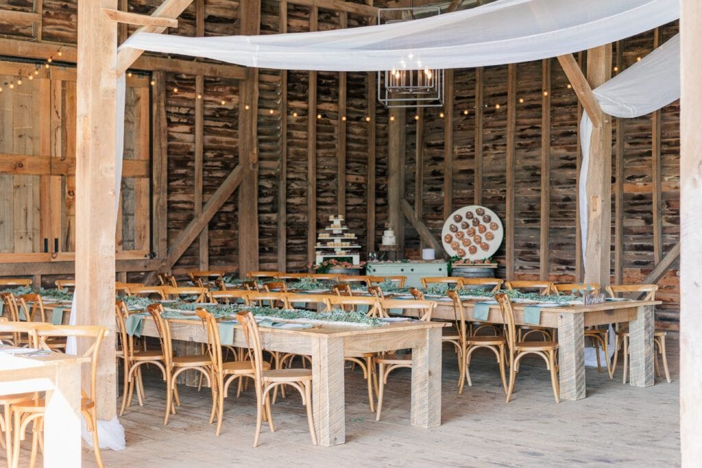 Farmhouse table style reception setup in the barn at Sky Ridge Farm, a barn wedding venue in Waynesboro, VA, near the Blue Ridge Mountains. Photo by Wedding Phootography by Jo Mahaney, a Virginia wedding photographer.