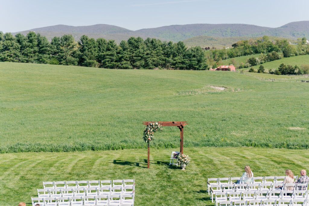 The blue ridge mountains behind the ceremony set up at Sky Ridge Farm, a barn wedding venue in Waynesboro, VA, near the Blue Ridge Mountains. Photo by Wedding Phootography by Jo Mahaney, a Virginia wedding photographer.