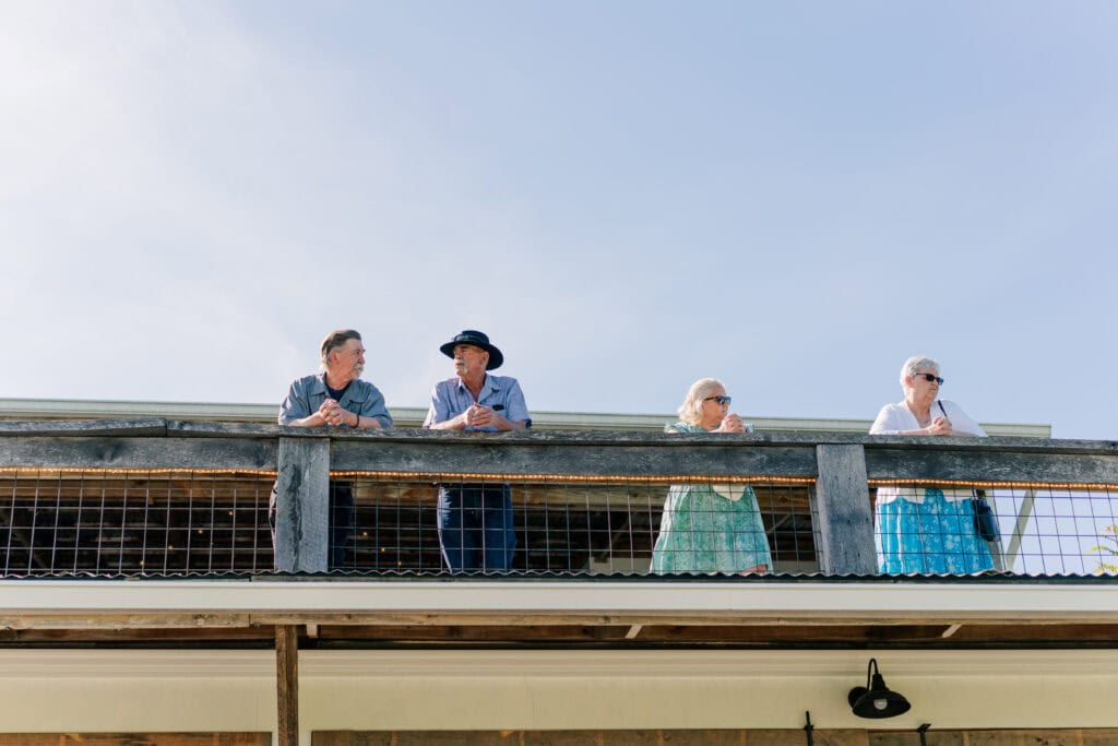 Guests watch ceremony prep from the balcony behind the barn at Sky Ridge Farm, a barn wedding venue in Waynesboro, VA, near the Blue Ridge Mountains. Photo by Wedding Phootography by Jo Mahaney, a Virginia wedding photographer.