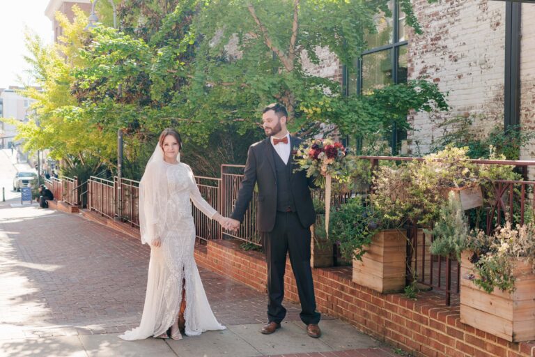 A bride and groom kiss in front of a brick wall.